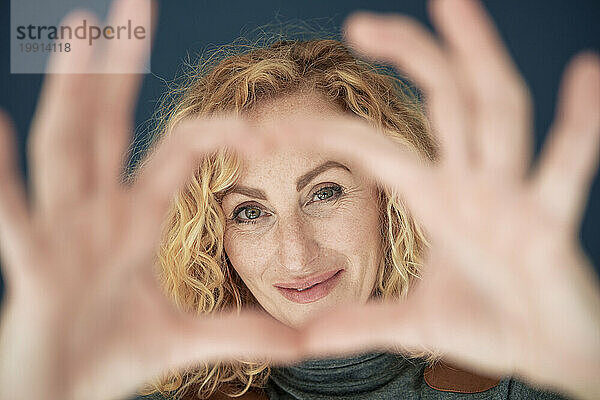 Smiling woman gesturing heart shape