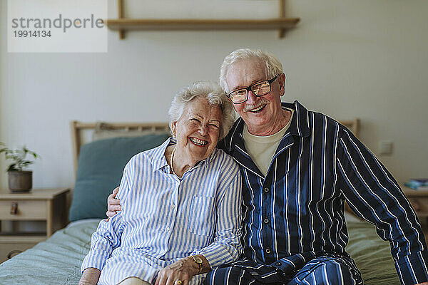 Glückliches älteres Paar  das zu Hause zusammen im Bett sitzt