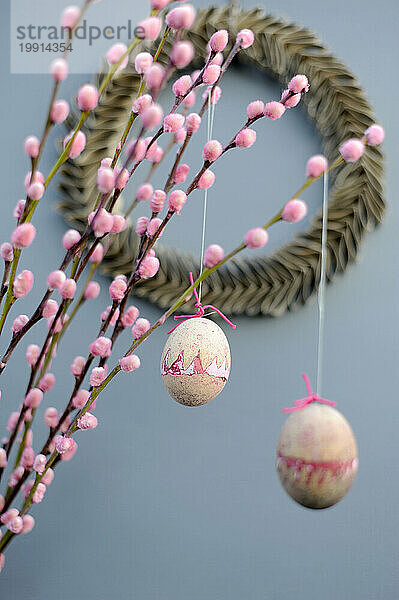 Ostereier hängen an rosa Weidenkätzchenzweigen