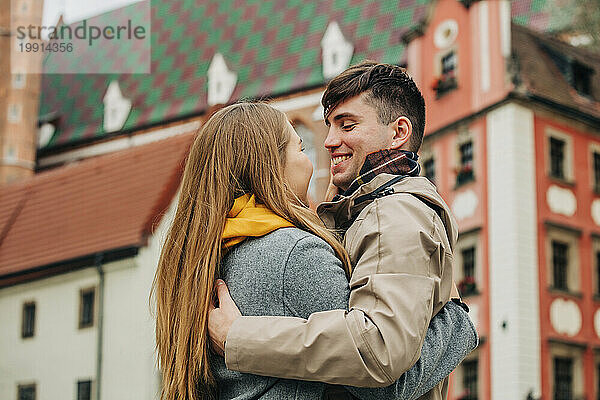 Glücklicher Mann umarmt Freundin vor Gebäude
