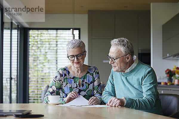 Älteres Paar sitzt zu Hause am Tisch und prüft Dokument