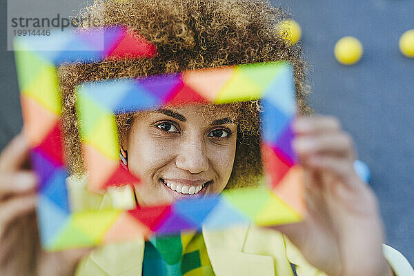 Smiling woman looking through multi colored toy