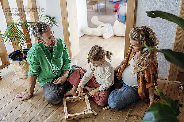 Girl playing block game with parents at home