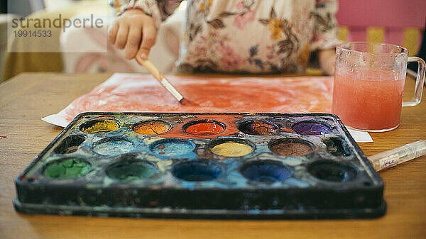 Mädchen malt zu Hause mit Wasserfarben auf Papier