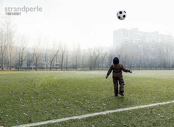 Boy throwing ball in air at soccer field