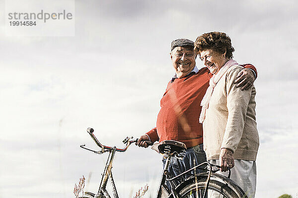 Happy senior couple spending leisure time under cloudy sky