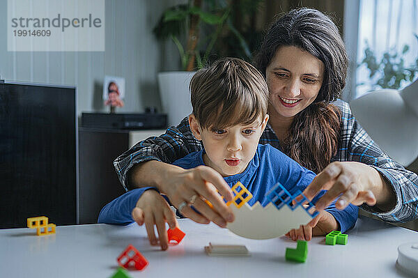 Mutter und Sohn spielen zu Hause mit Bauklötzen