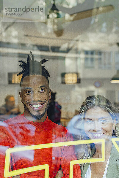 Smiling multiracial business colleagues looking through window