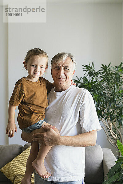 Großvater hält Enkel im Wohnzimmer zu Hause