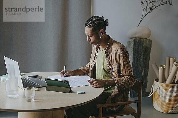 Junger Mann schreibt in ein Buch und lernt zu Hause