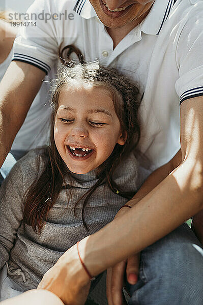 Lächelndes Mädchen  das an einem sonnigen Tag Spaß mit seinem Vater hat