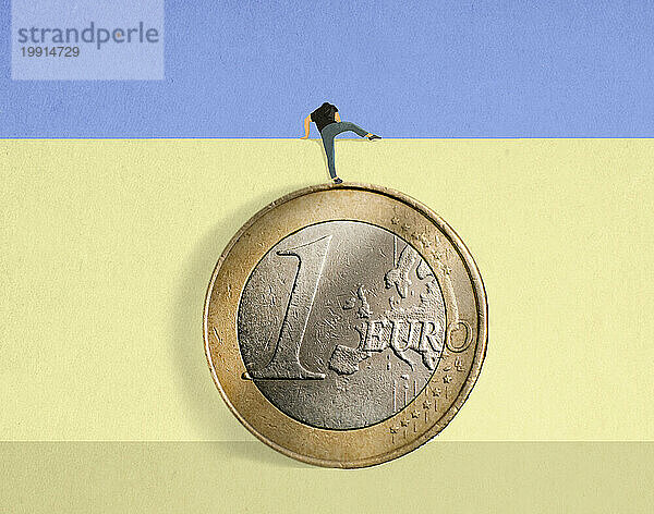 Mann steht auf übergroßer Euro-Münze und klettert über Mauer