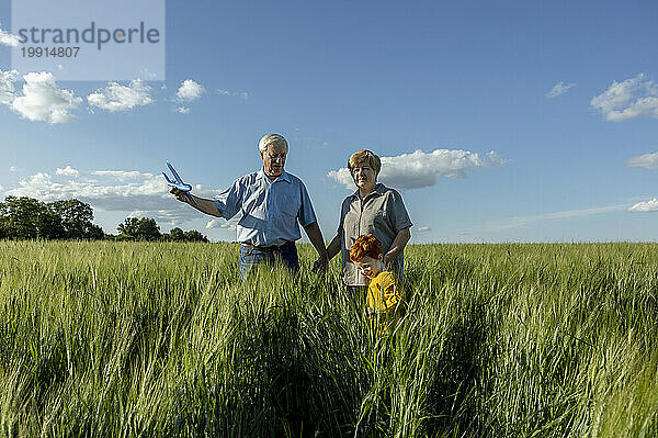 Elderly couple having fun with grandson in field