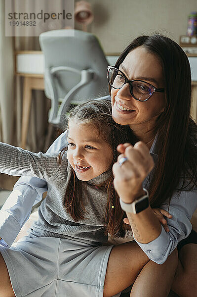 Lächelnde Mutter und Tochter spielen zu Hause Steinpapierschere