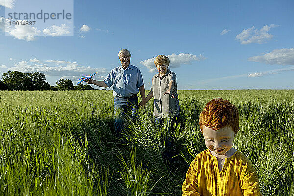 Senior couple spending leisure time with grandson in field