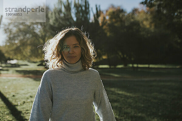 Lächelnde Frau im grauen Pullover im Herbstpark