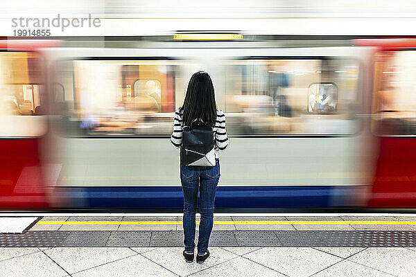 Frau mit Rucksack steht vor der U-Bahn am Bahnhof