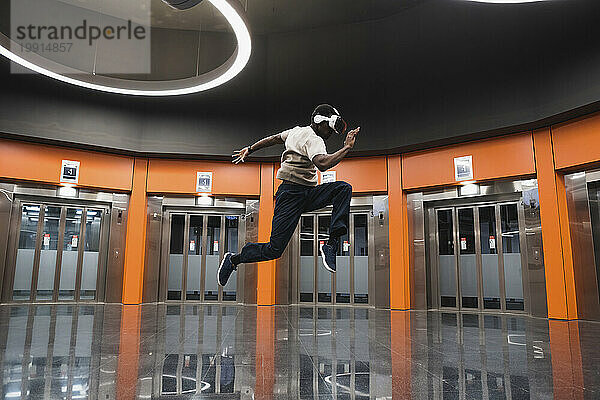 Young man wearing Virtual Reality Simulator jumping at Metro Station