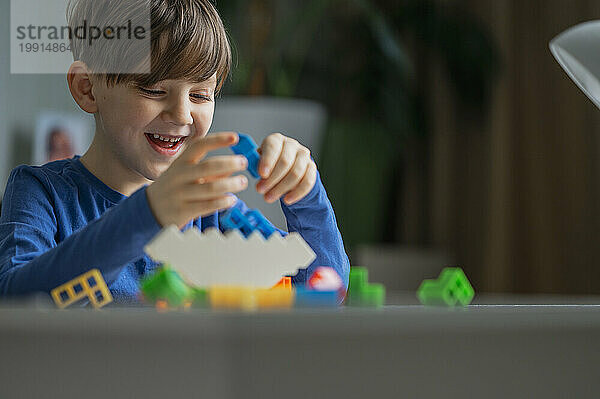 Cheerful boy playing with toy blocks at home