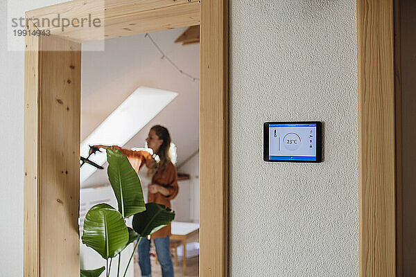 Hausautomations-App auf Tablet-PC mit Frau im Hintergrund
