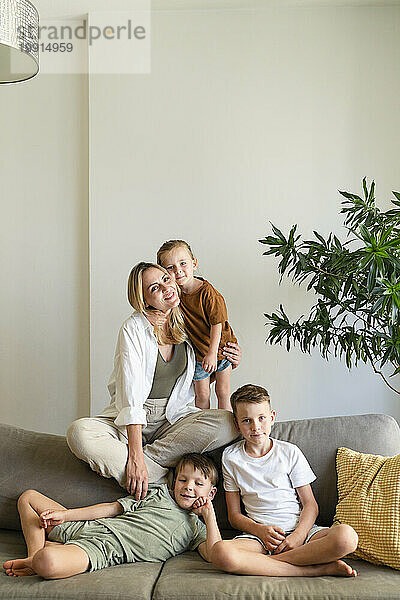 Mutter mit drei Söhnen sitzt zu Hause auf dem Sofa im Wohnzimmer