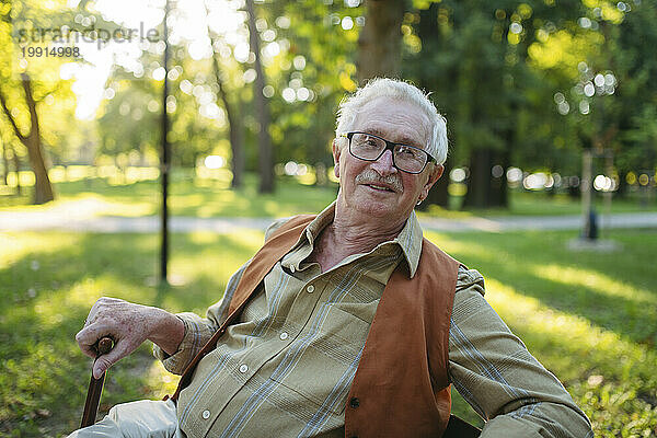 Lächelnder älterer Mann sitzt im Park
