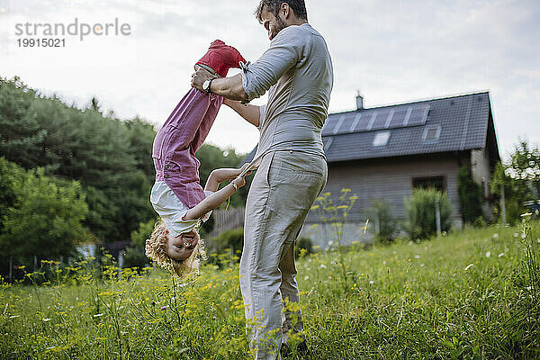 Vater und kleine Tochter amüsieren sich vor dem Haus ihrer Familie