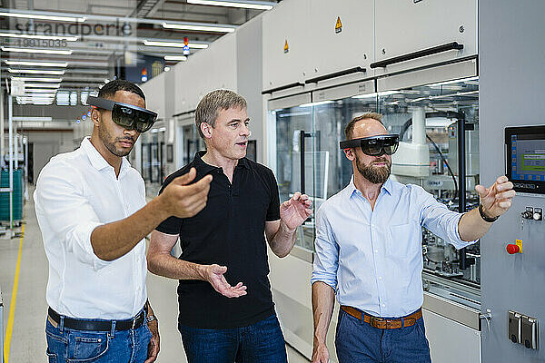 Zwei Techniker tragen Augmented-Reality-Brillen in einer Fabrik und interagieren mit Kollegen