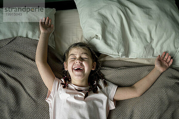Mädchen liegt auf dem Bett und lacht zu Hause