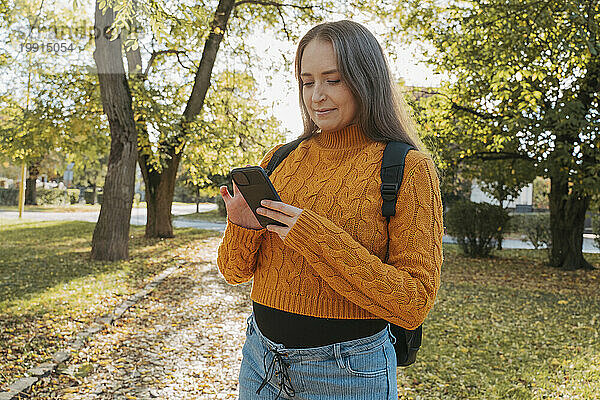 Frau benutzt Smartphone im Herbstpark