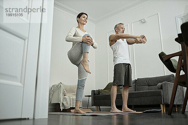 Couple doing stretching exercises in morning at home