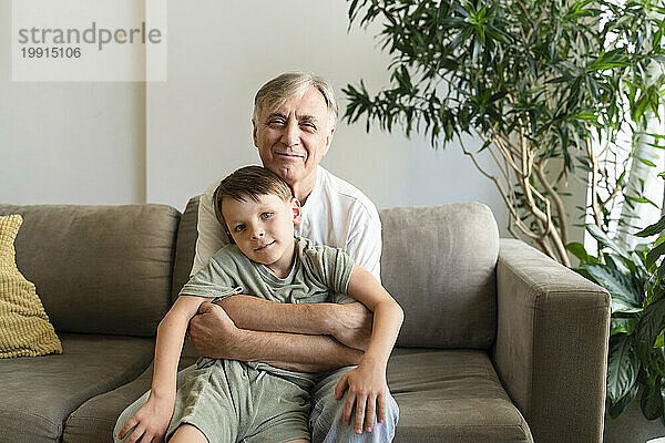 Großvater umarmt seinen Enkel zu Hause auf dem Sofa