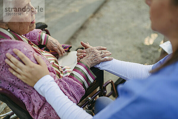 Gesundheitshelfer hält Händchen und tröstet ältere Frau