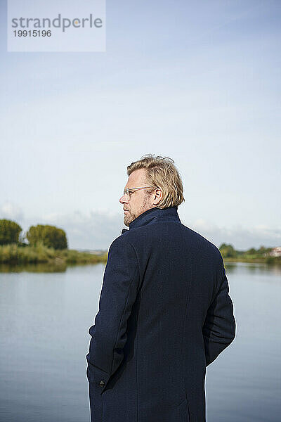 Contemplative businessman standing in front of river