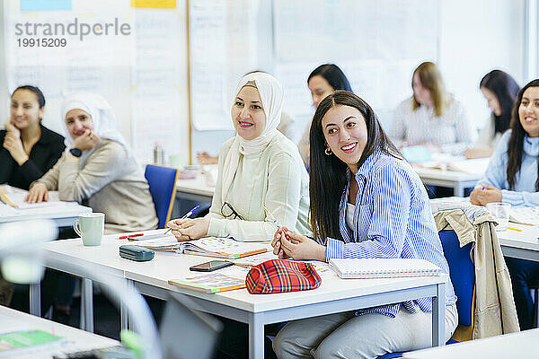 Lächelnde multiethnische Schüler am Schreibtisch lernen im Klassenzimmer