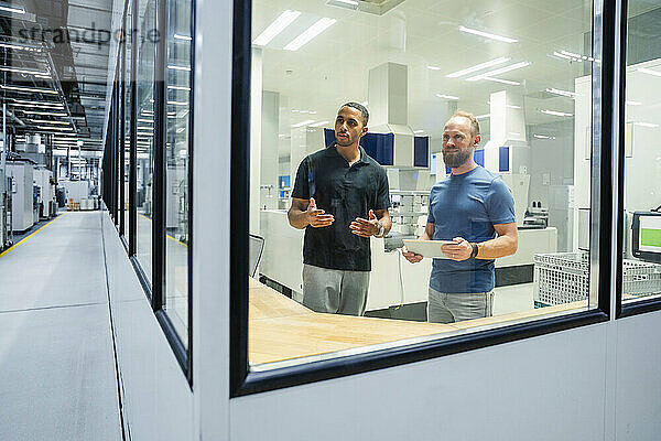 Zwei Kollegen mit digitalem Tablet bei einer Besprechung in einer Fabrik