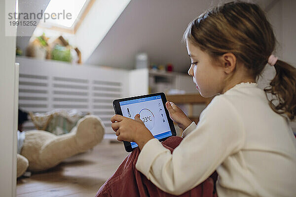 Mädchen regelt die Temperatur per App auf dem Tablet-PC im Dachgeschoss