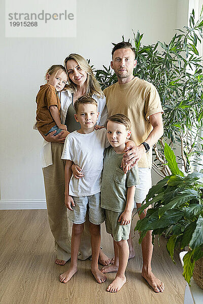 Lächelnde Familie mit Kindern  die zu Hause im Wohnzimmer stehen