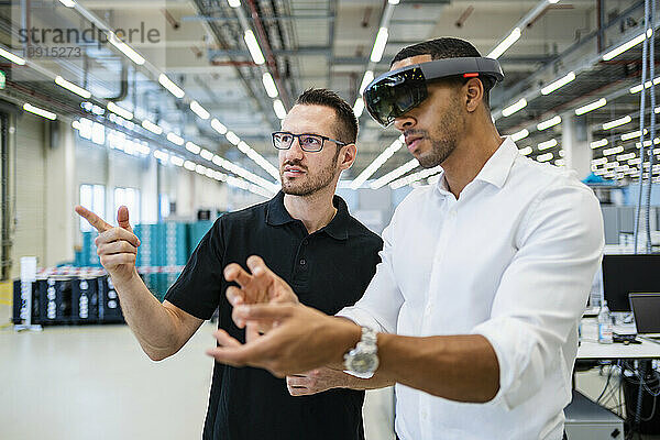Techniker mit Augmented-Reality-Brille interagiert in einer Fabrik mit Kollegen