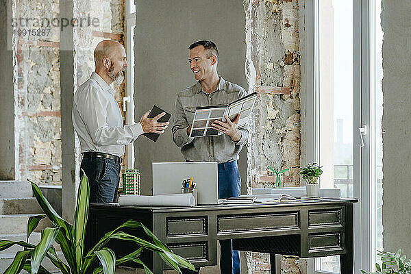 Glückliche Architekten diskutieren gemeinsam am Schreibtisch im Büro