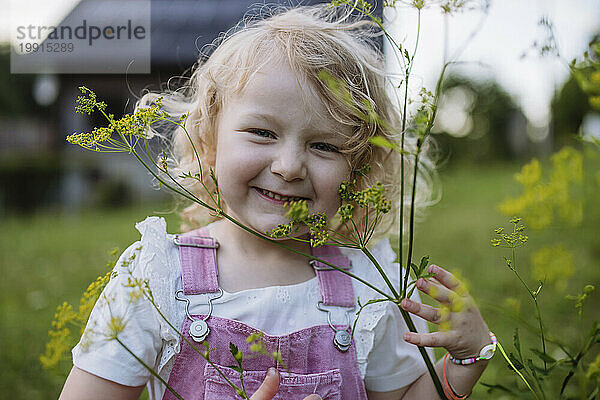 Niedliches kleines Mädchen vor ihrem Familienhaus mit Blumen