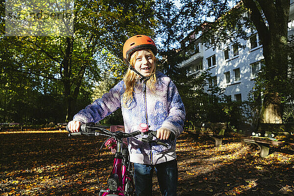Lächelndes Mädchen hält Fahrrad im Park