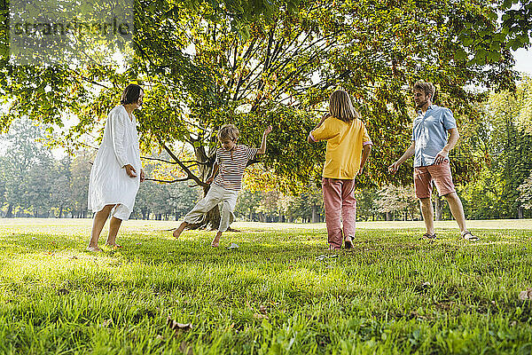 Glückliche Familie genießt das Wochenende beim Spielen auf dem Rasen im Park