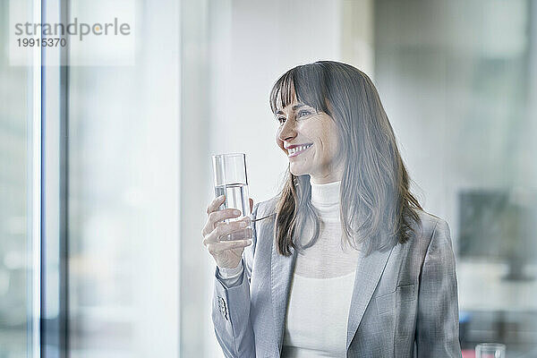 Glückliche Geschäftsfrau hält ein Glas Wasser