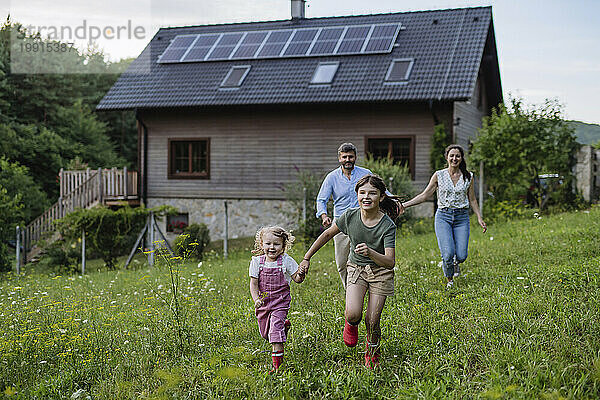 Happy girls running in garden of sustainable family home