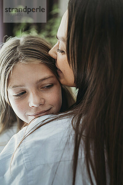 Liebevolle Mutter umarmt Tochter zu Hause
