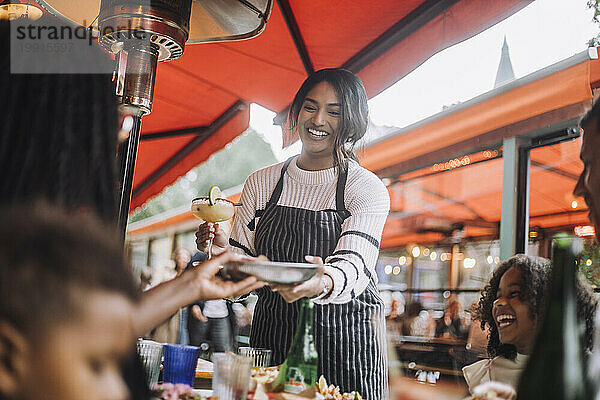 Lächelnde Kellnerin serviert den Kunden Speisen und Getränke und hat Spaß im Restaurant