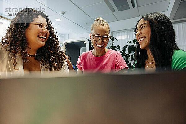 Fröhliche  gemischtrassige Geschäftsfrauen  die am Arbeitsplatz lachen