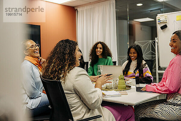 Fröhliche Geschäftsfrauen diskutieren bei einem Treffen im Büro