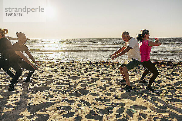 Team trainiert gemeinsam auf Sand während einer Gruppentrainingseinheit am Strand